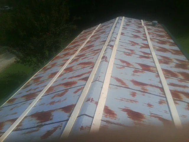 Rusted metal roof panels with new wood purlins before replacement — Storm Damage Roof Repair in Blanchard by Roofing Brothers